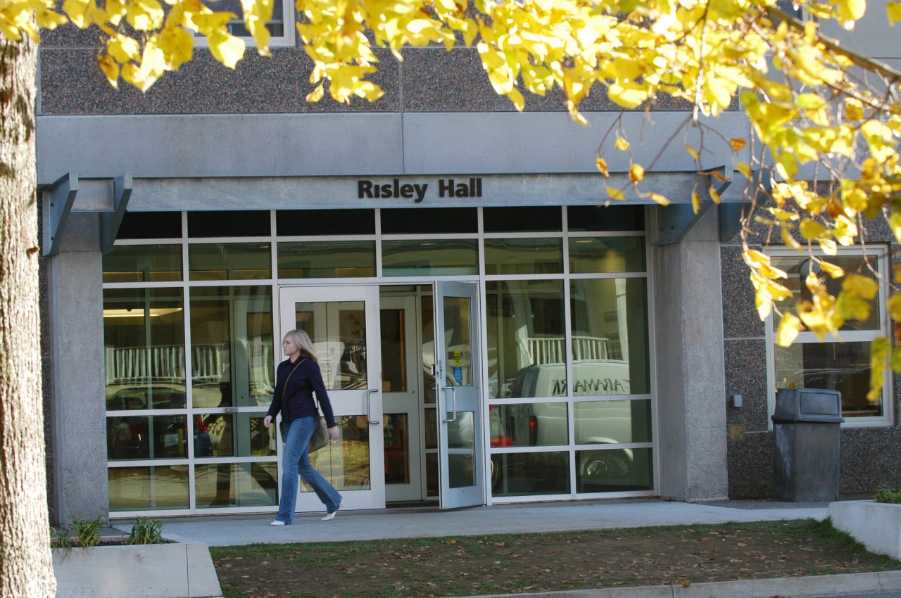 A student exits through the glass doors on the front of Risley Hall.