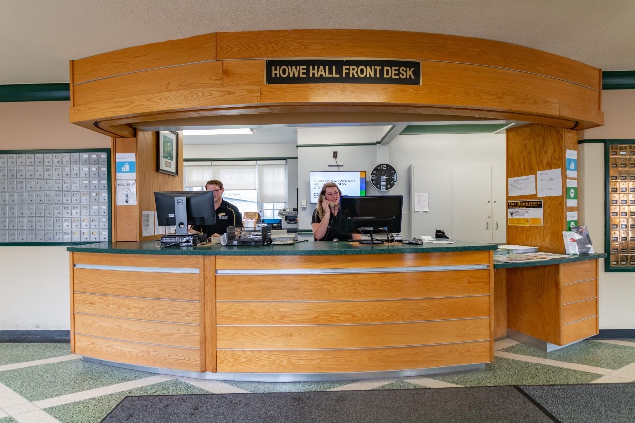 The front desk at Howe Hall with two staff members working behind the desk.  