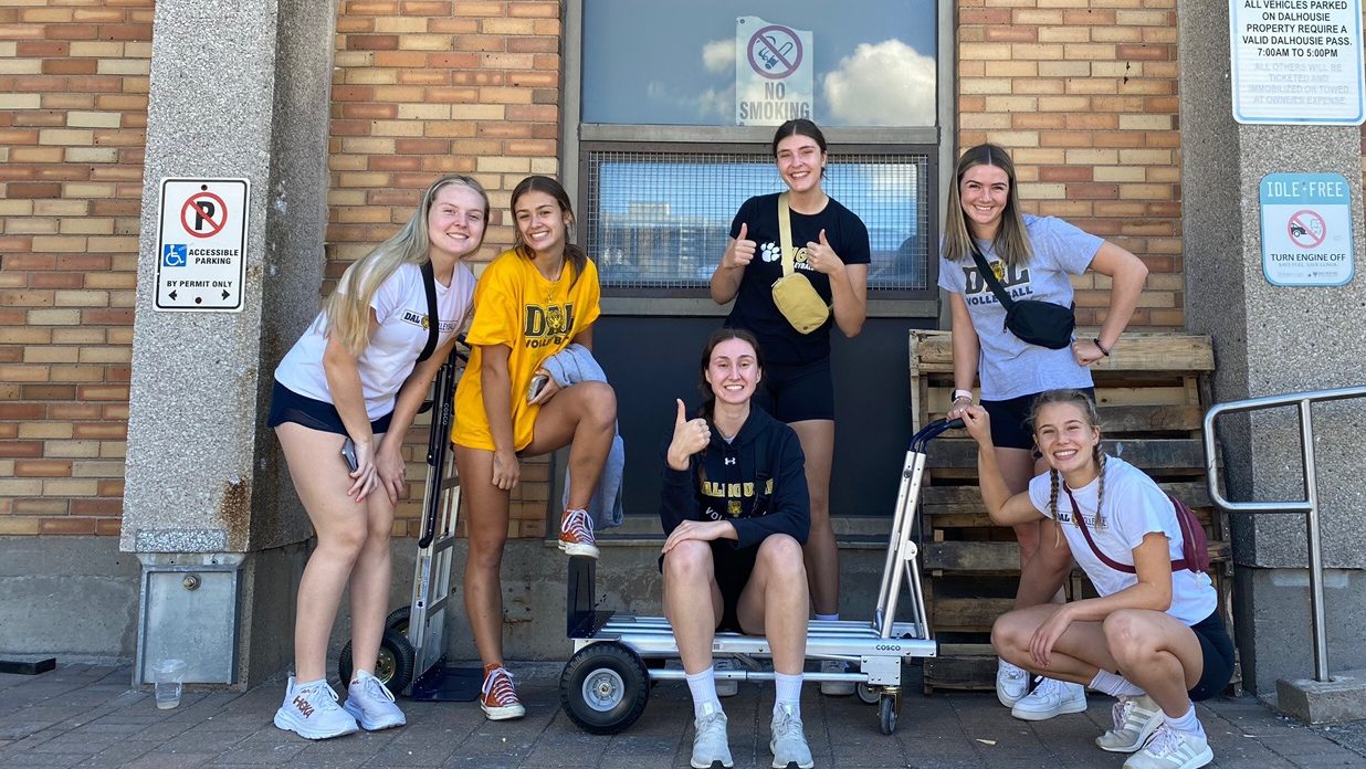 Three students chat as they walk through the lobby of the Rowe Management Building.