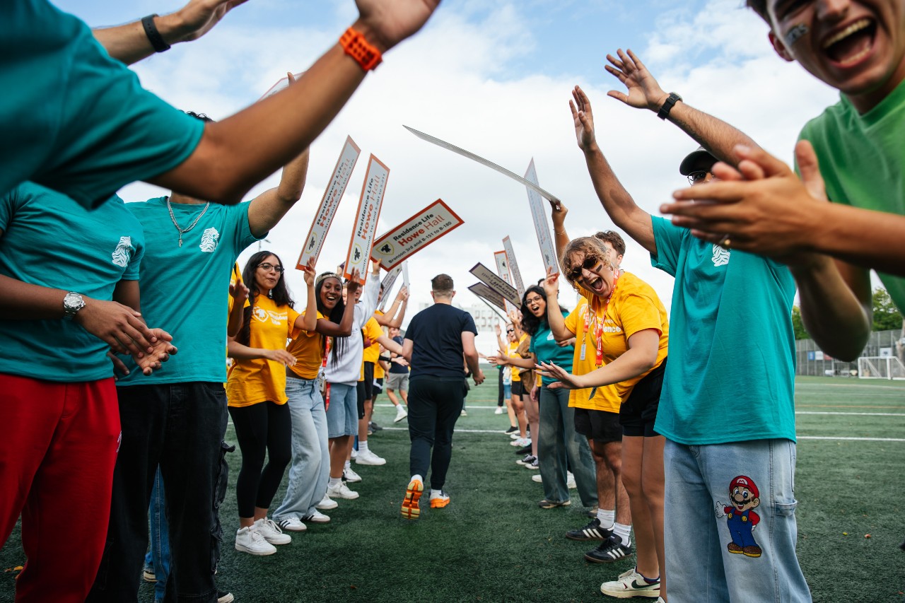 Members of the residence life team hold signs for buildings and houses on Wickwire Field, welcoming residents