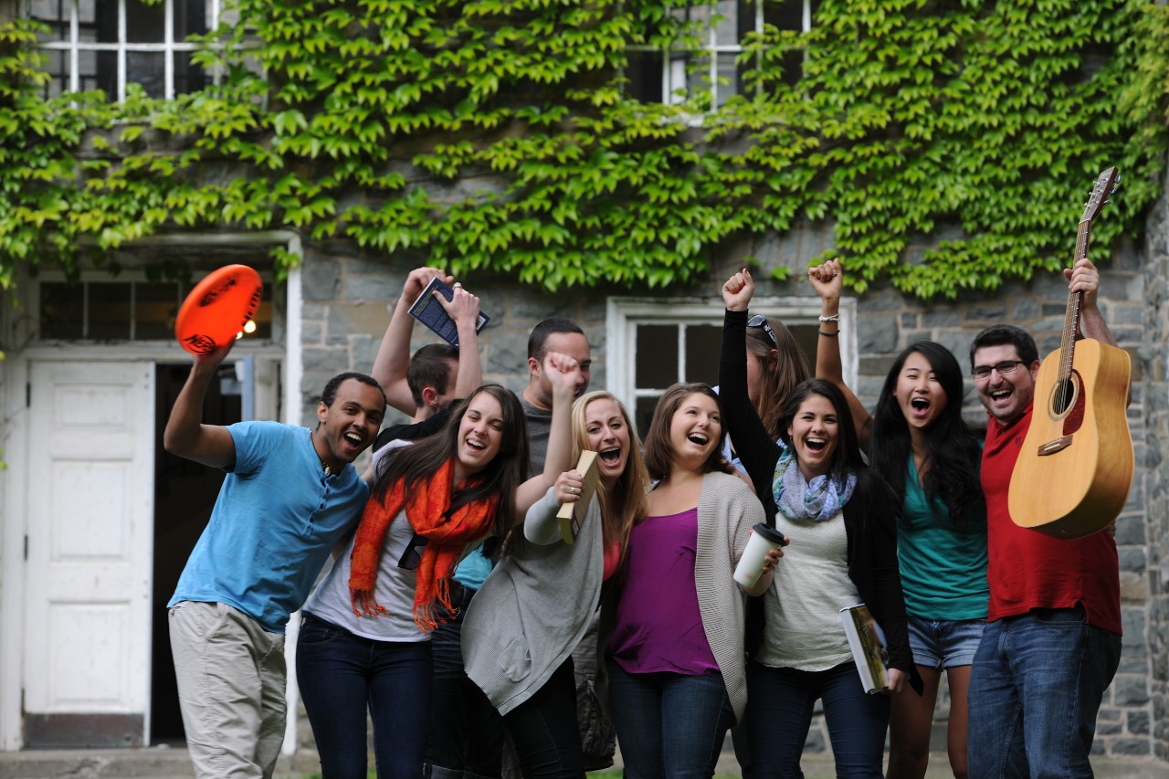 A team of Residence Life staff members smile and cheer for the camera