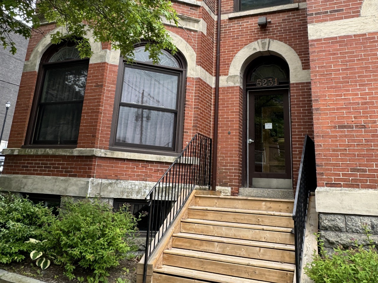 The front entry at Grad House with wooden steps and an arched door