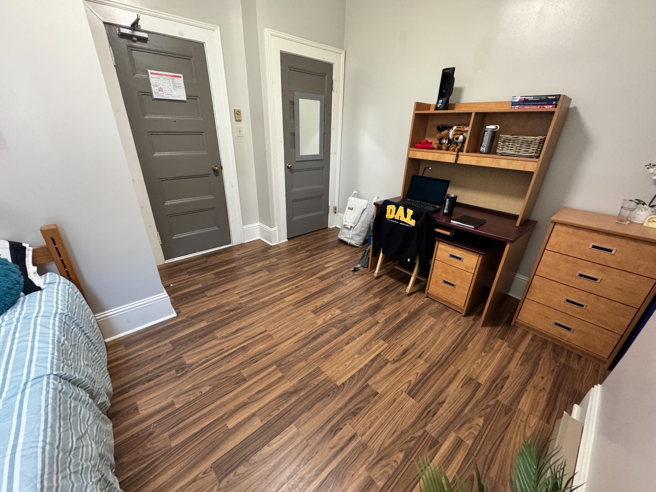 A single room at Grad House, furnished with bed, desk, storage, and a built-in closet.