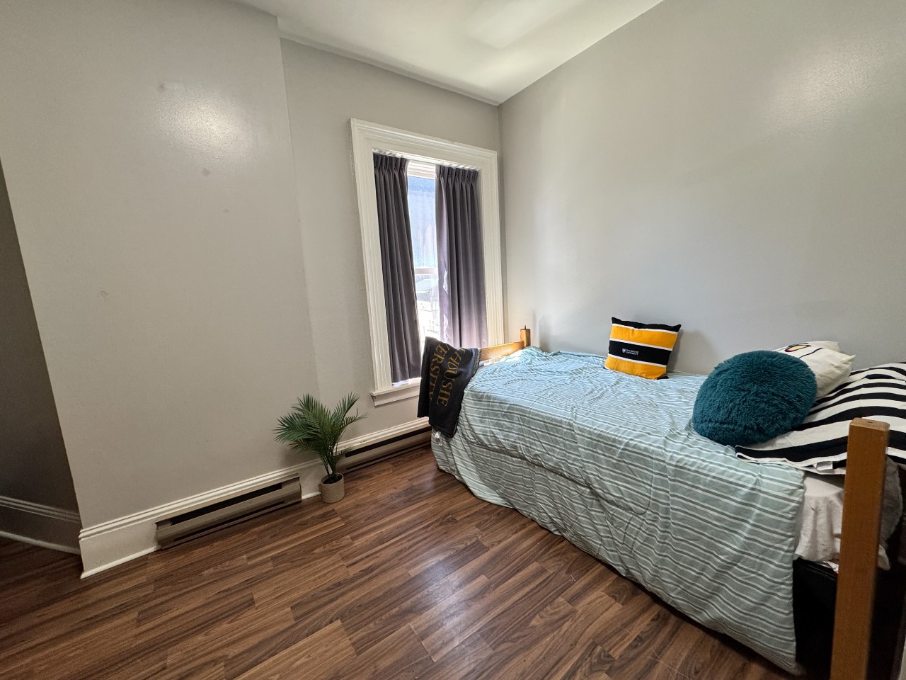 A single room at Grad House, furnished with bed, desk, storage, and a built-in closet.