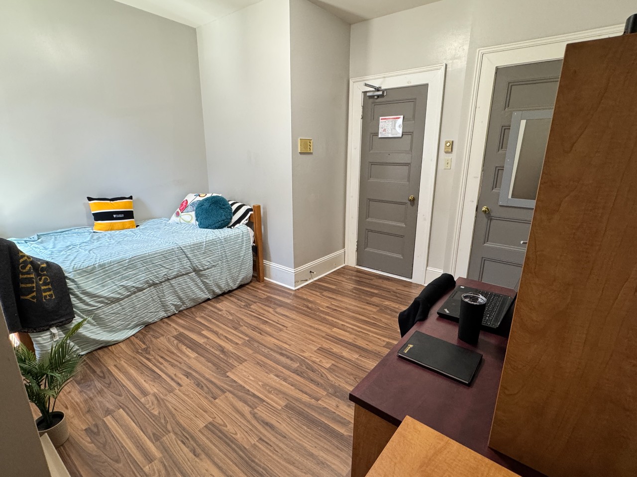 A single room at Grad House, furnished with bed, desk, storage, and a built-in closet.