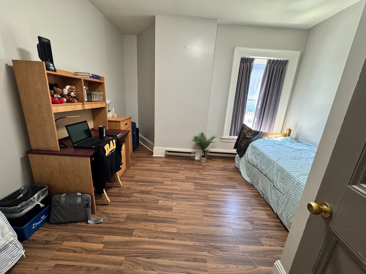 A single room at Grad House, furnished with bed, desk, storage, and a built-in closet.