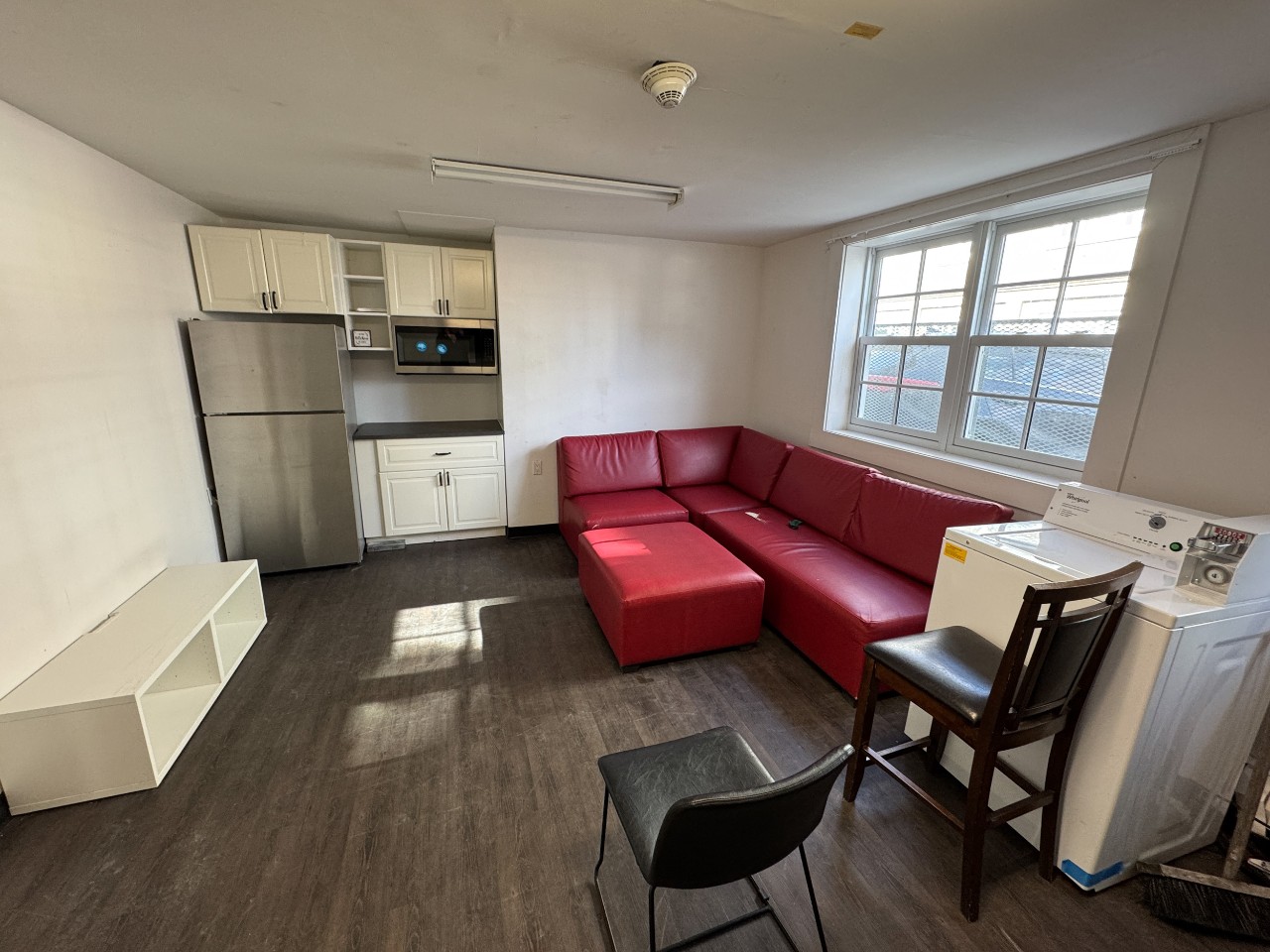 The common lounge in Studley House with red leather seating and a kitchenette