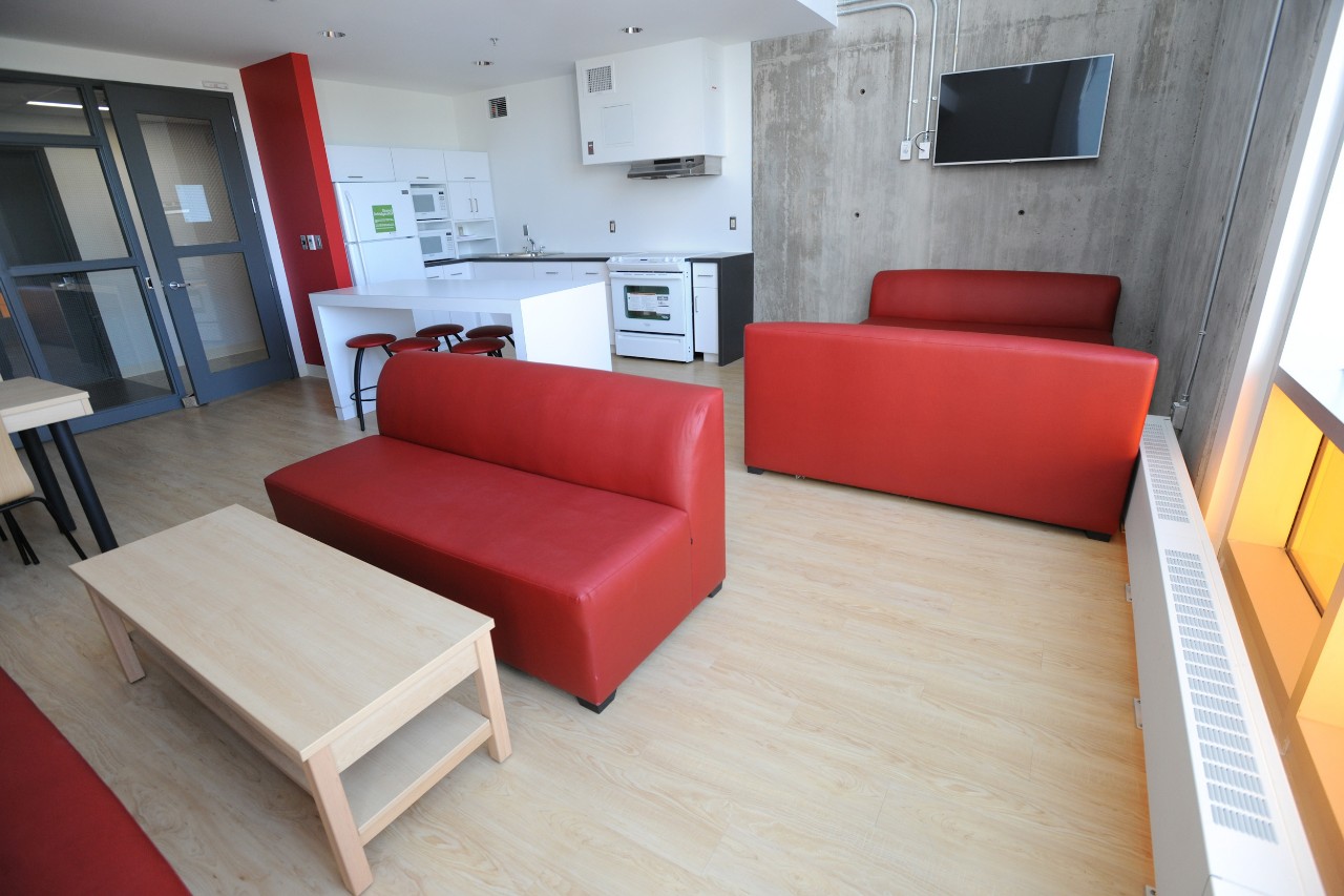 A kitchen lounge in LeMarchant Place, featuring red seating, a white kitchen island, and full kitchen