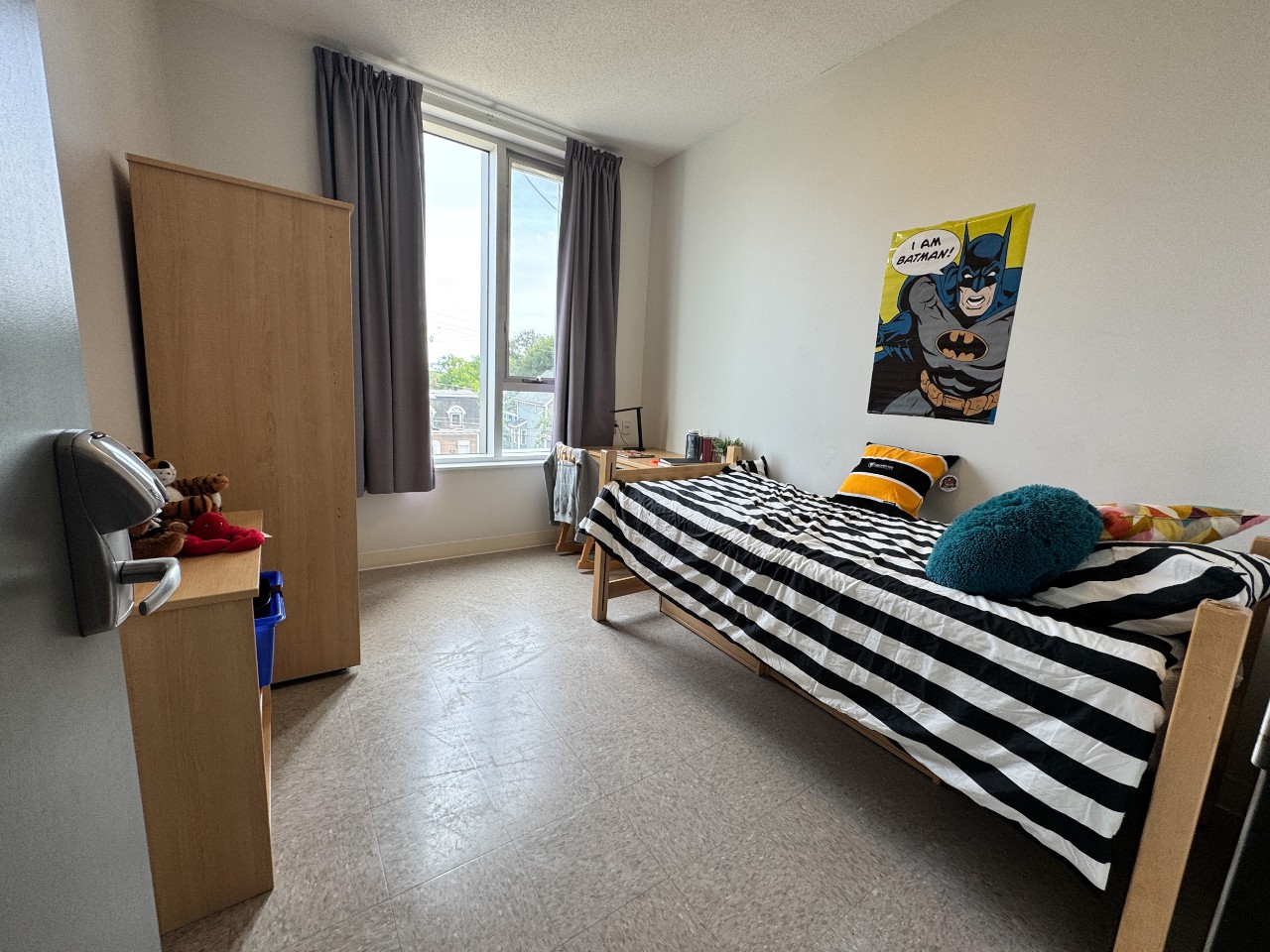 A bedroom in a 2-bedroom suite in LeMarchant Place with bed, desk, shelves, and wardrobe