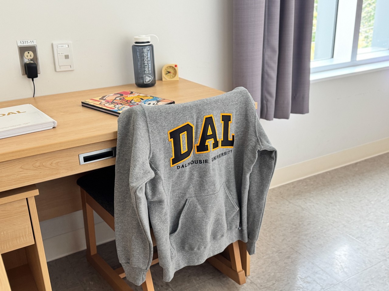 A bedroom in a 3-bedroom suite in LeMarchant Place featuring a bed, desk, wardrobe, and shelves.