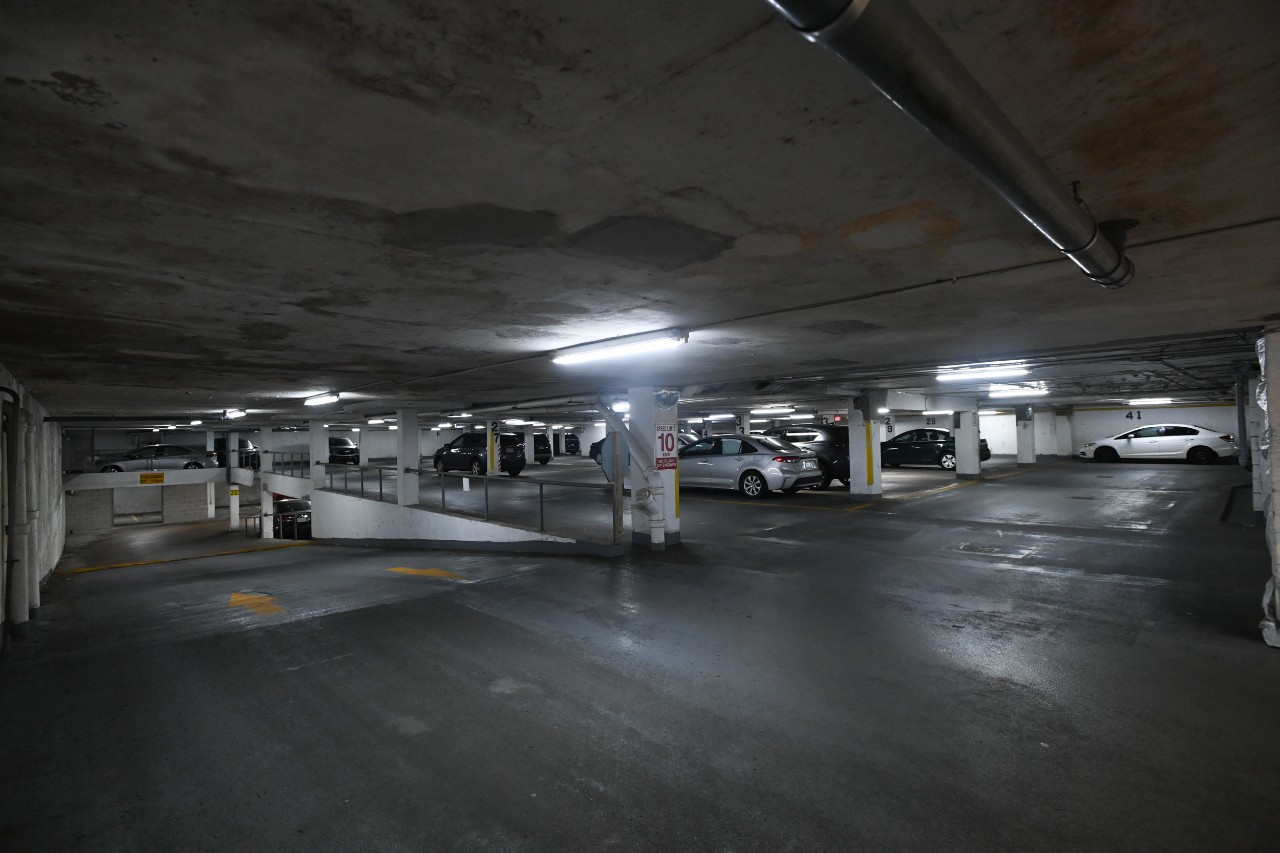 An underground parking garage with white pillars and a ramp leading to a lower level