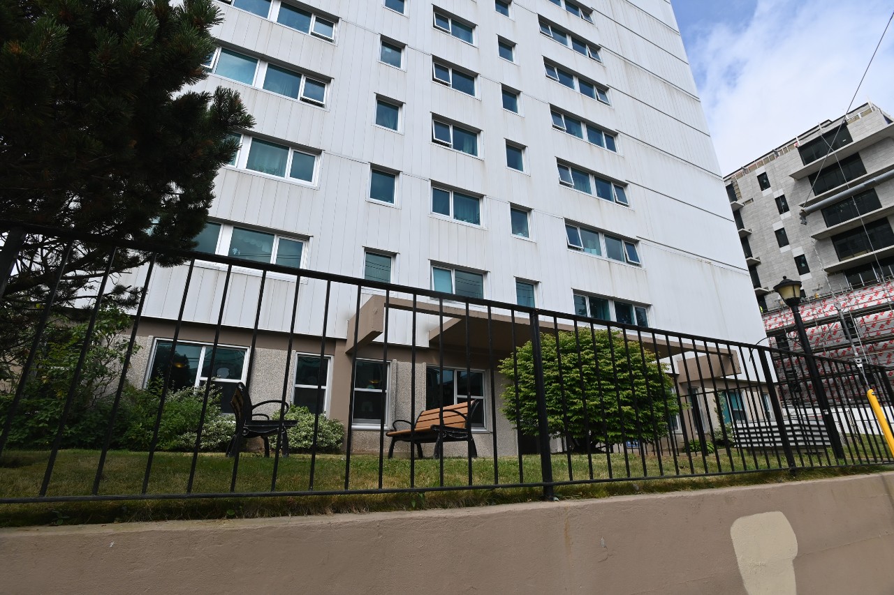 The shared courtyard is seen through a black rod iron fence along the sidewalk