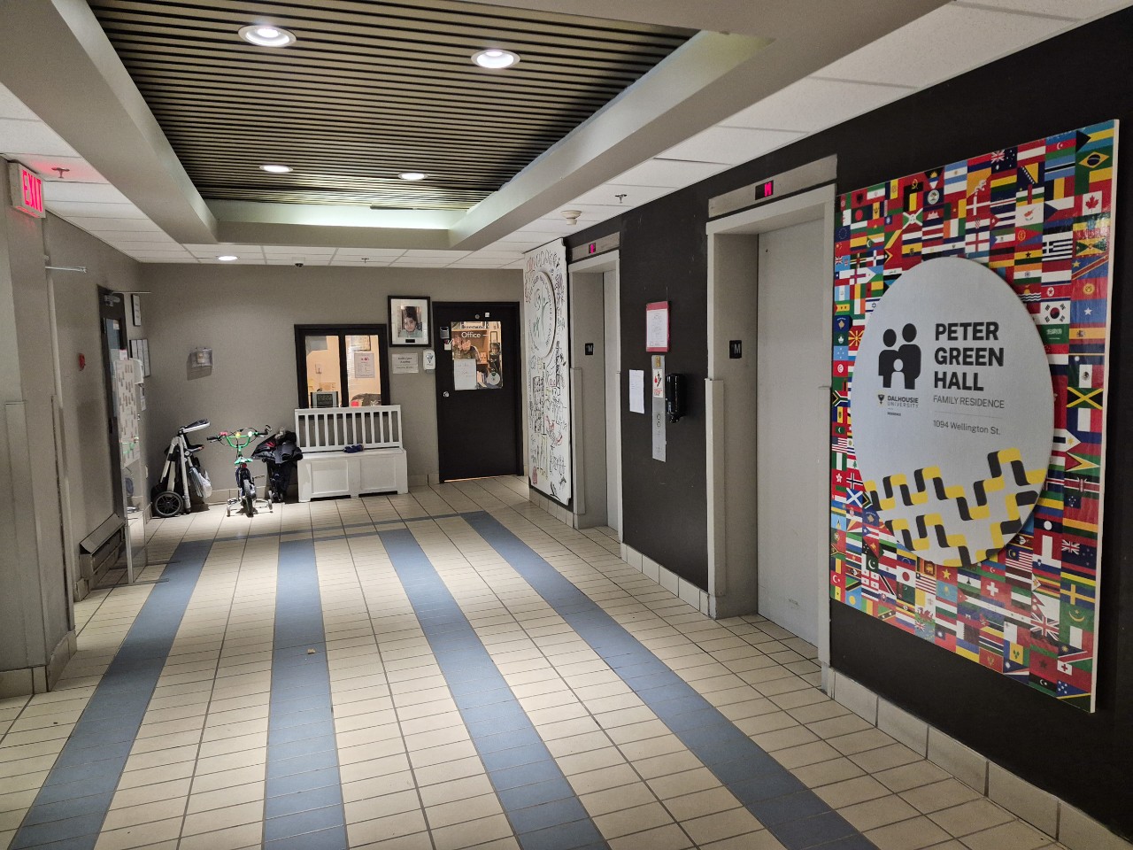 The lobby of Peter Green Hall has tile floor, 2 elevators, and a metal sign with the name of the building