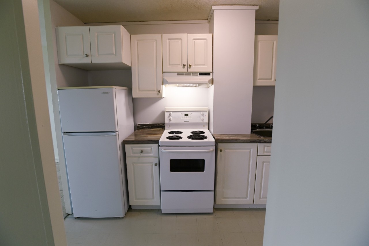 The full kitchen in a one-bedroom unit with white cupboards and appliances