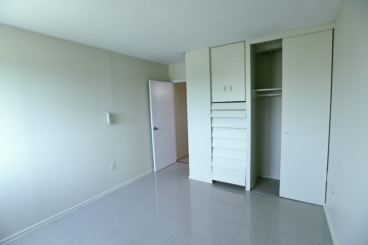 The bedroom of a one-bedroom unit with a large built-in closet with plenty of storage