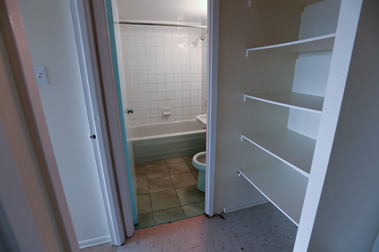 The bathroom and hall linen closet in a two-bedroom unit - including toilet, sink, and tub and plenty of shelving