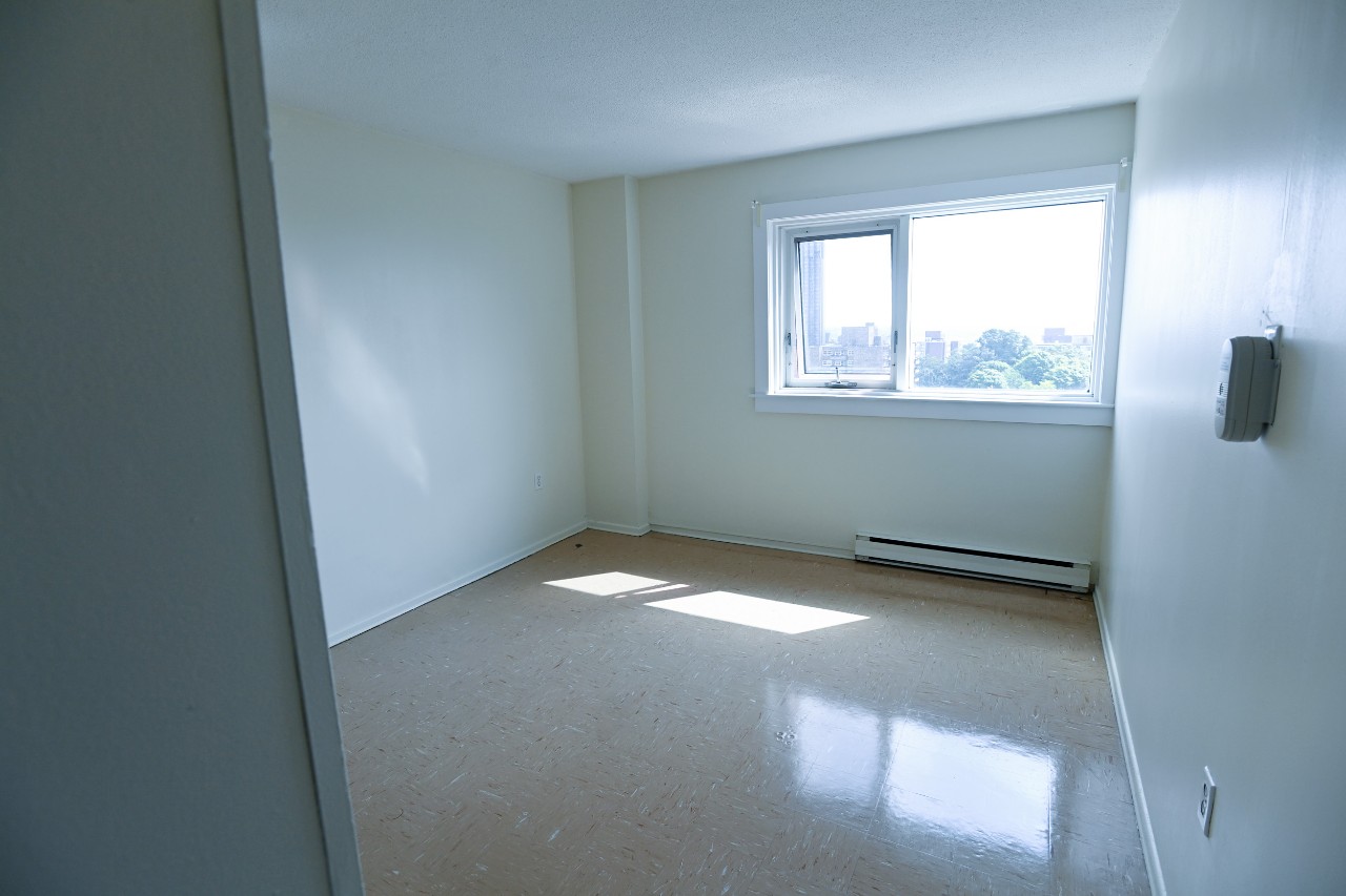 The second bedroom in a two-bedroom unit with a large window and glossy linoleum floors