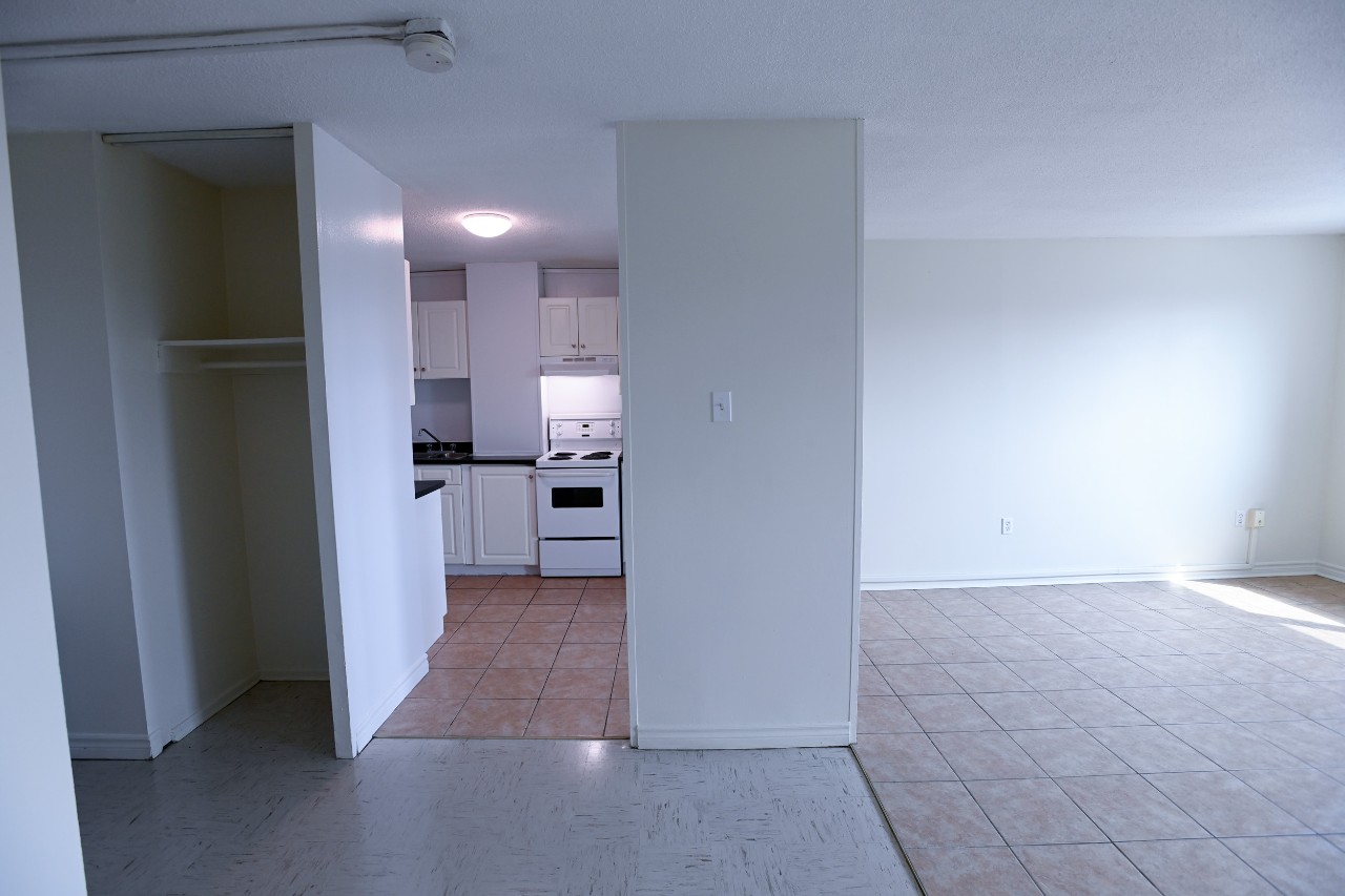 A view of the kitchen and living room in a two-bedroom unit, with tile floors and pale green walls