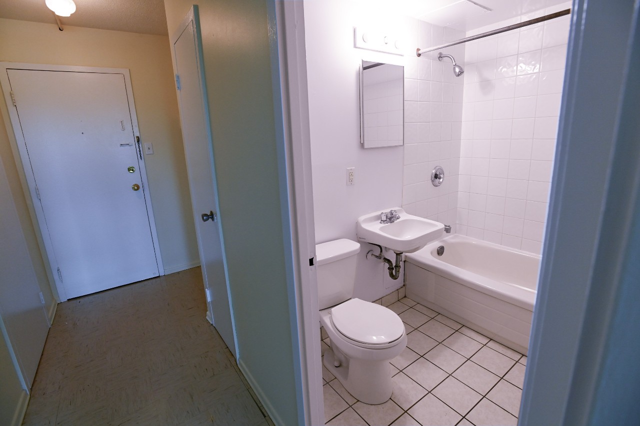 A full bath in a one-bedroom unit, with white toilet, sink, and tub