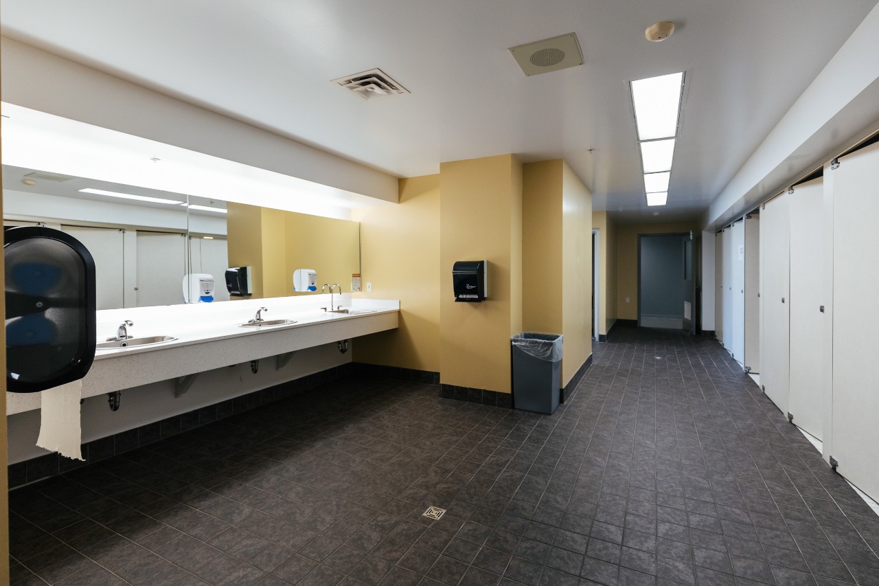 An all-gender bathroom in Risley Hall with full length stalls for privacy and a long counter with sinks.