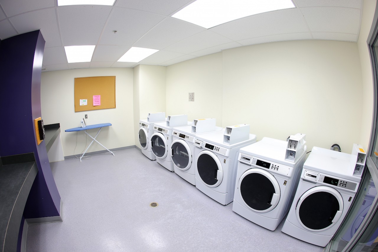 Several coin-operated washing machines in a laundry room in Risley Hall