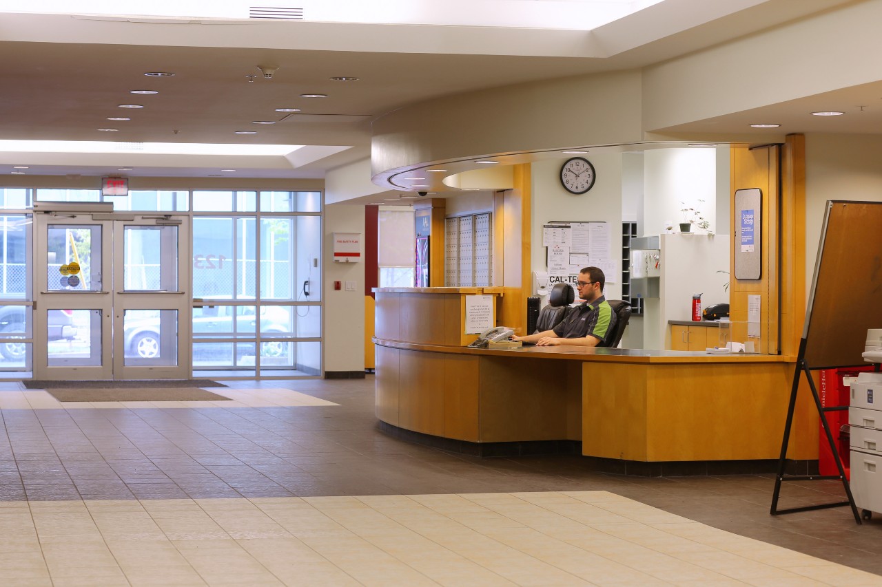 The honey-coloured wood curved front desk in the lobby in Risley Hall