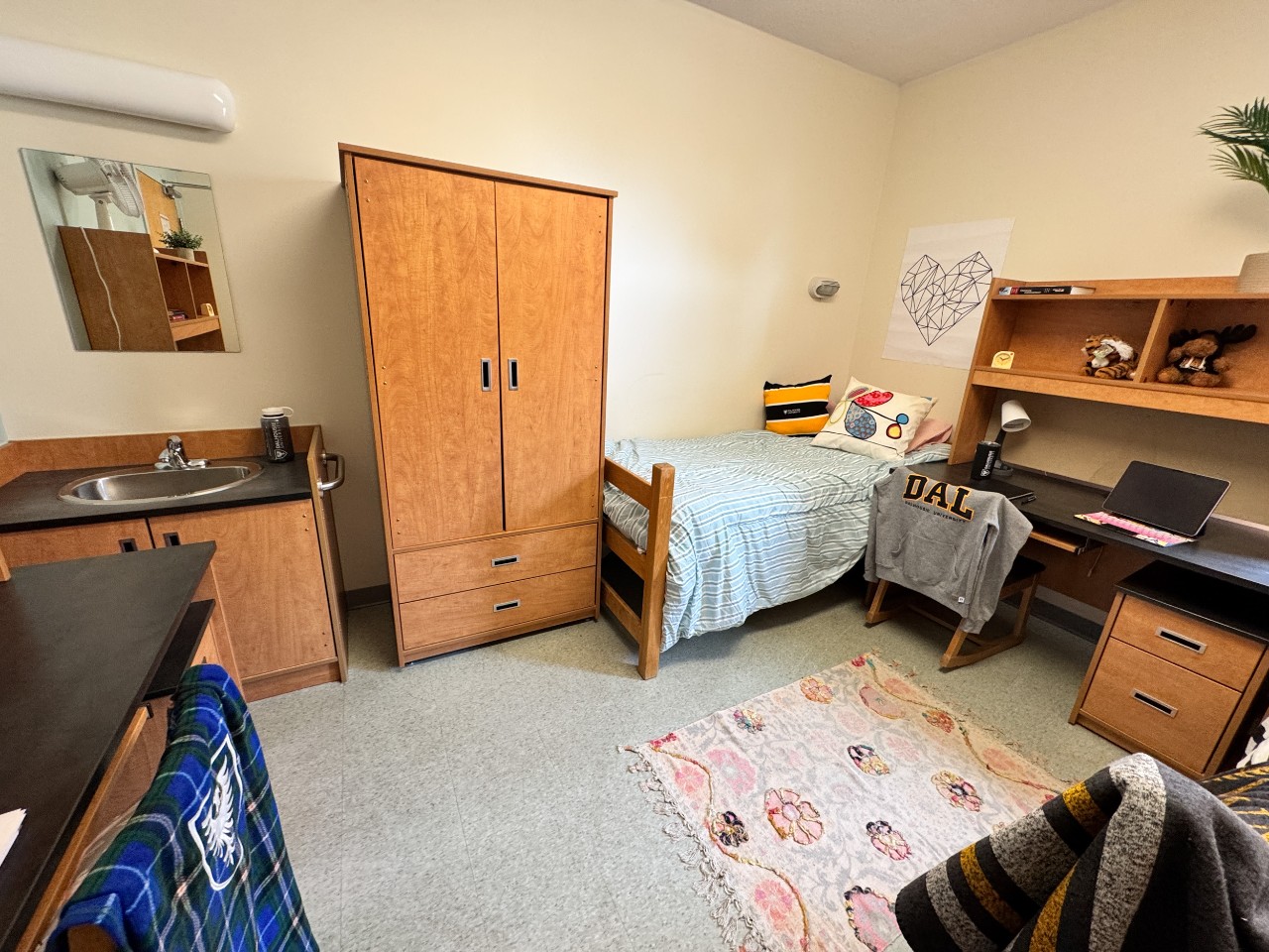 One side of a double room in Risley Hall, with a bed, wardrobe, desk, and sink.