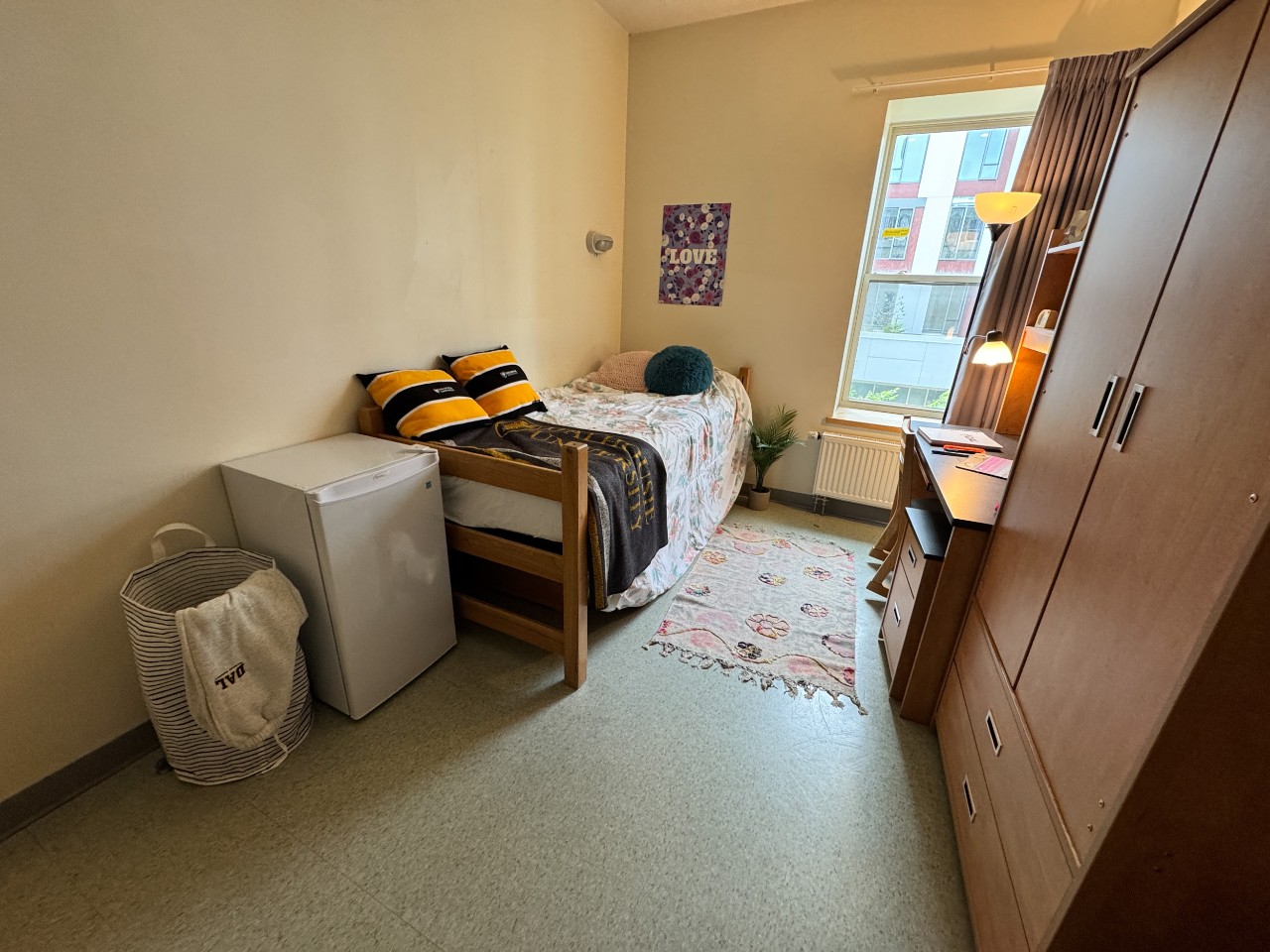 A single room in Risley Hall with an adjustable bed, desk, wardrobe, and a mini fridge. 