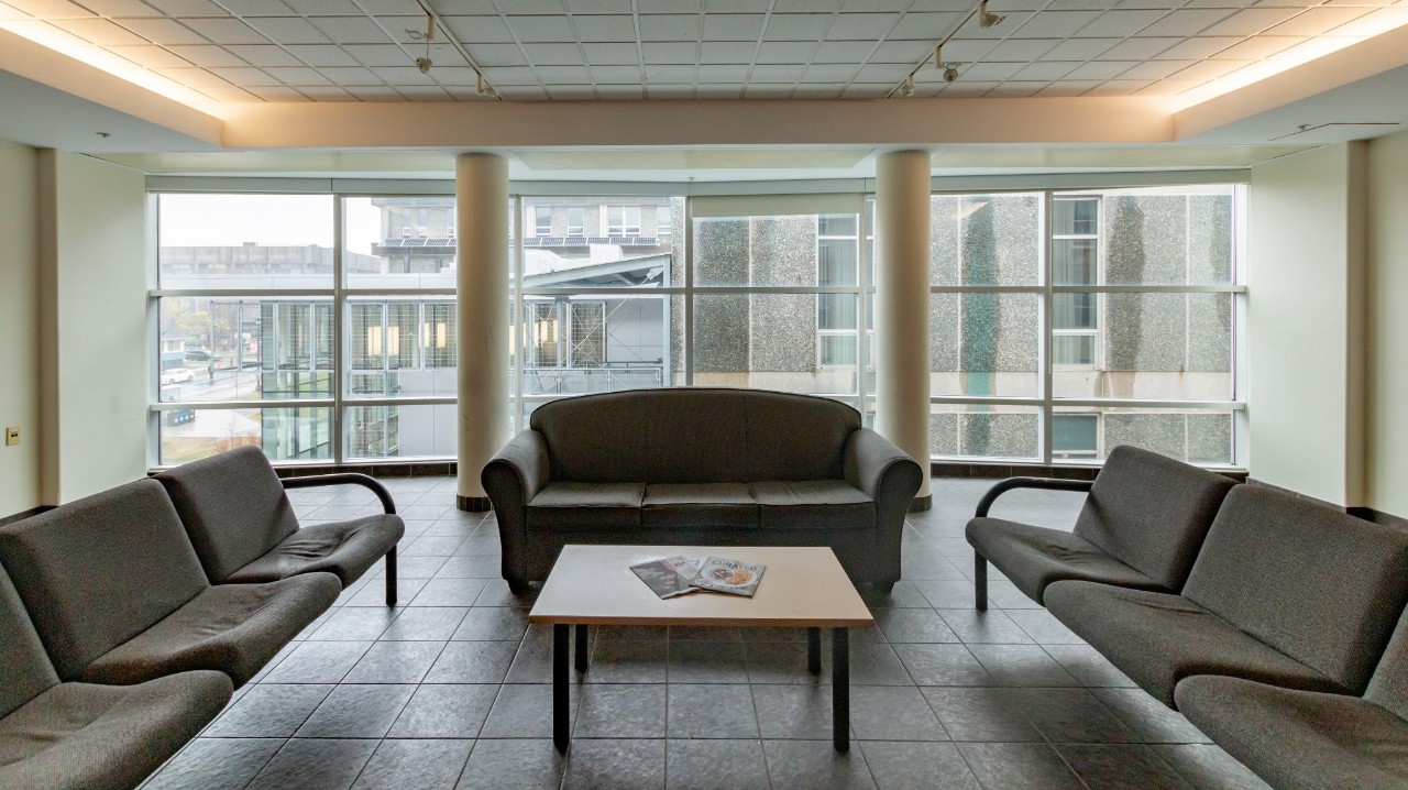A medium-sized lounge in Risley Hall with grey sofas, floor to ceiling windows, and a square coffee table.