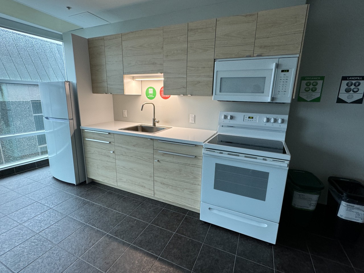 A full kitchen in a lounge in Risley Hall, with modern light wood cabinets and white appliances