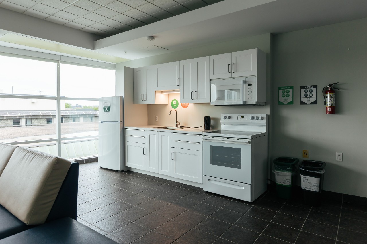 A full kitchen in a lounge in Risley Hall, with modern white cabinets and white appliances