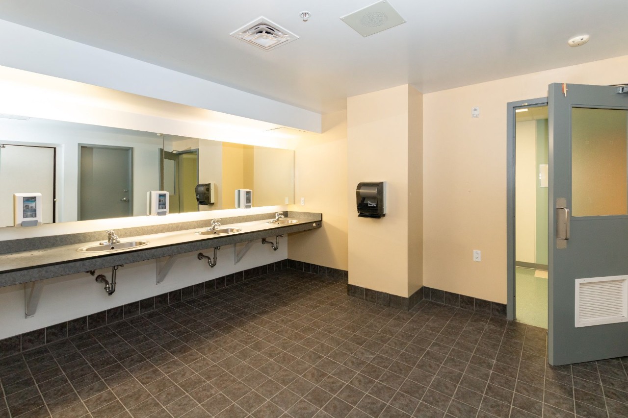 An all-gender bathroom in Risley Hall a long counter and mirror with several sinks. 