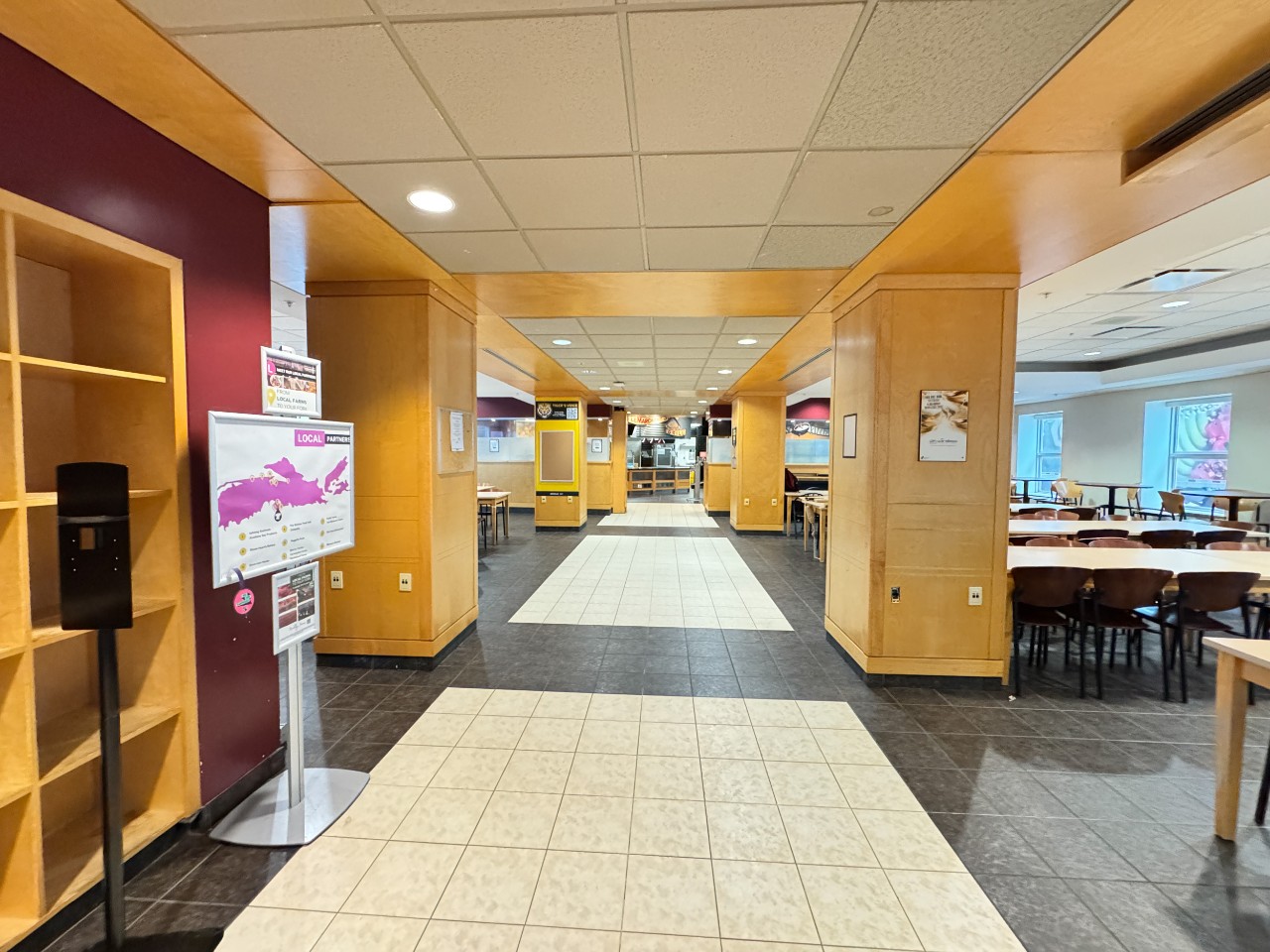 Risley dinign hall as seen from the entrance, with a long tiled hall and tables on either side.