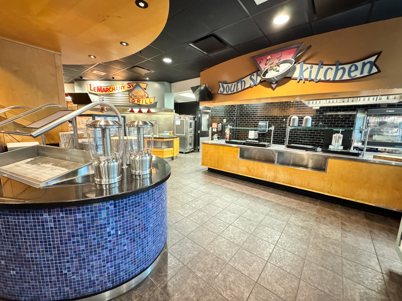 The servery in Risley Hall, with several stations, as well as a salad bar in the centre of the room with blue tiles. 