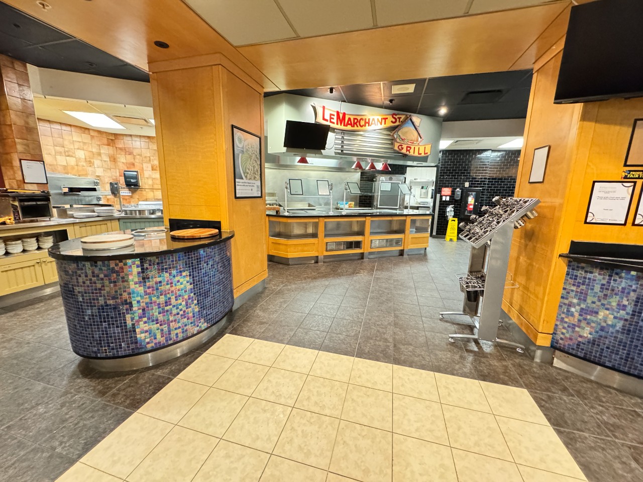 The servery in Risley Hall, with several stations, as well as a salad bar in the centre of the room with blue tiles. 