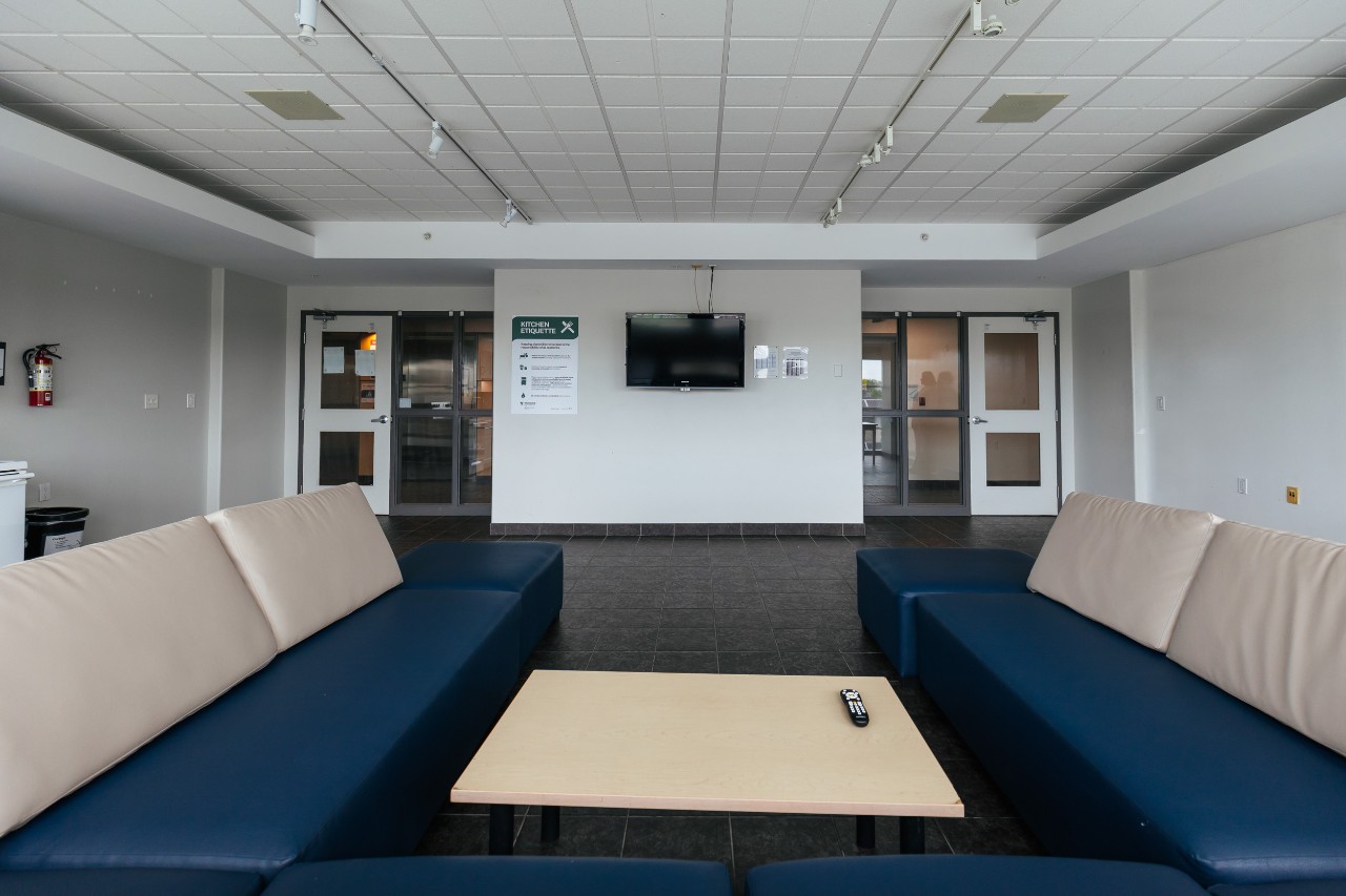 A large lounge on a residence floor in Risley Hall - with a u-shaped sectional sofa and television on the wall