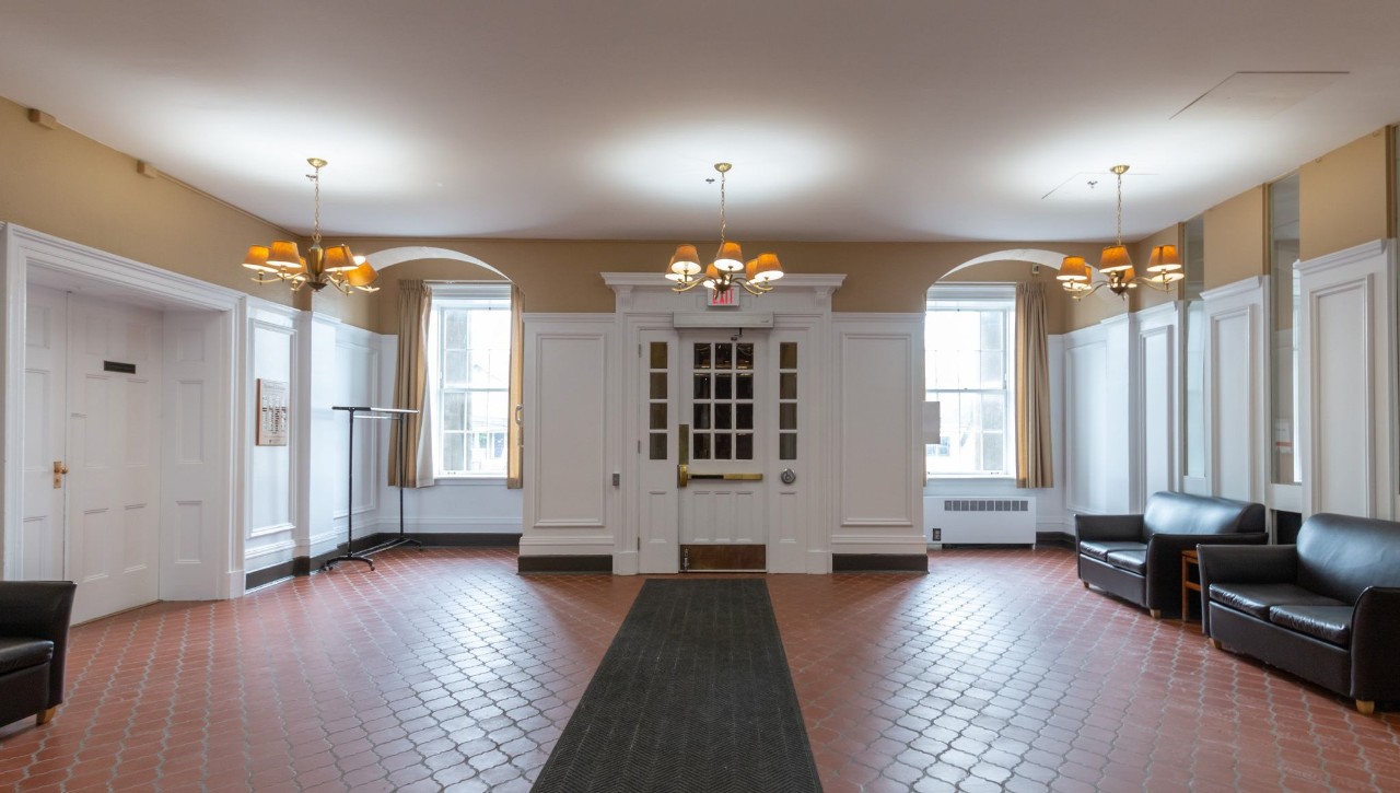 The lobby area has plenty of ornate wood trim, a large front entrance, and terracotta-style tiles on the floor.