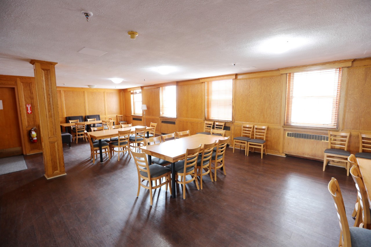 A large study lounge in Shirreff Hall, with long wooden tables, wood panelling and dark floors. 