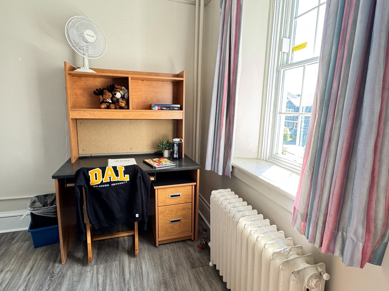 The desk in this single room is next to a large window, with plenty of natural light.