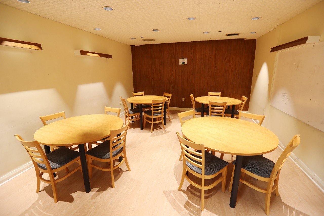 A small study lounge in Newcombe house has round wooden tables and chairs, with plenty of space for groups.