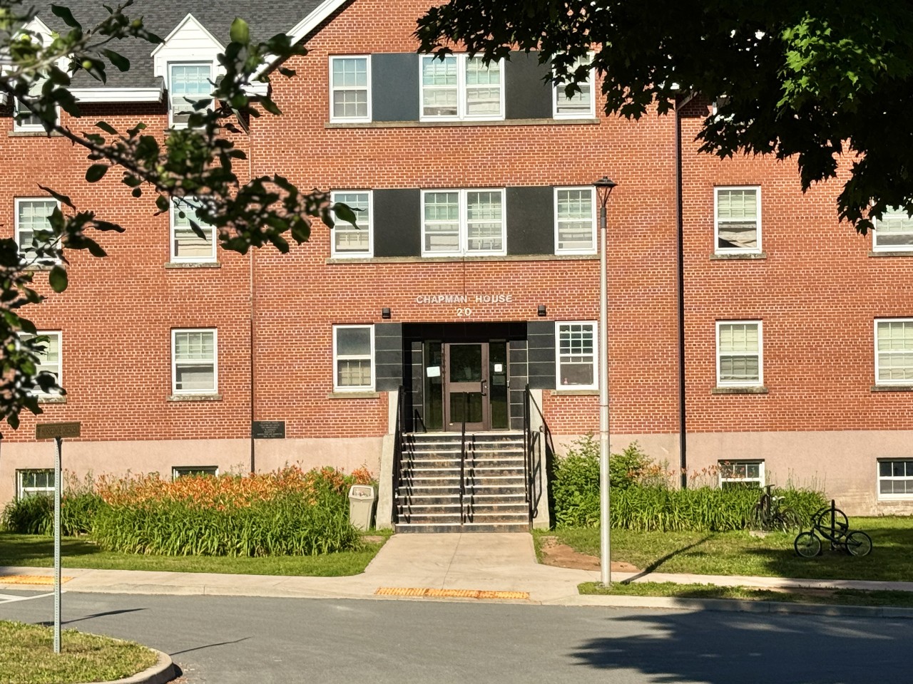 The red brick front of Chapman House seen through the trees on the Horseshoe