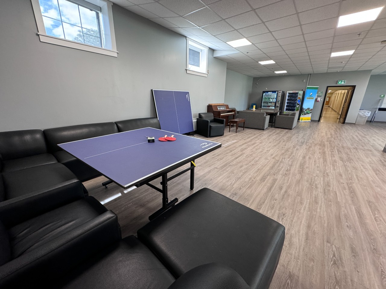 Black leather sofas and a table at one end of the Fraser House lounge.