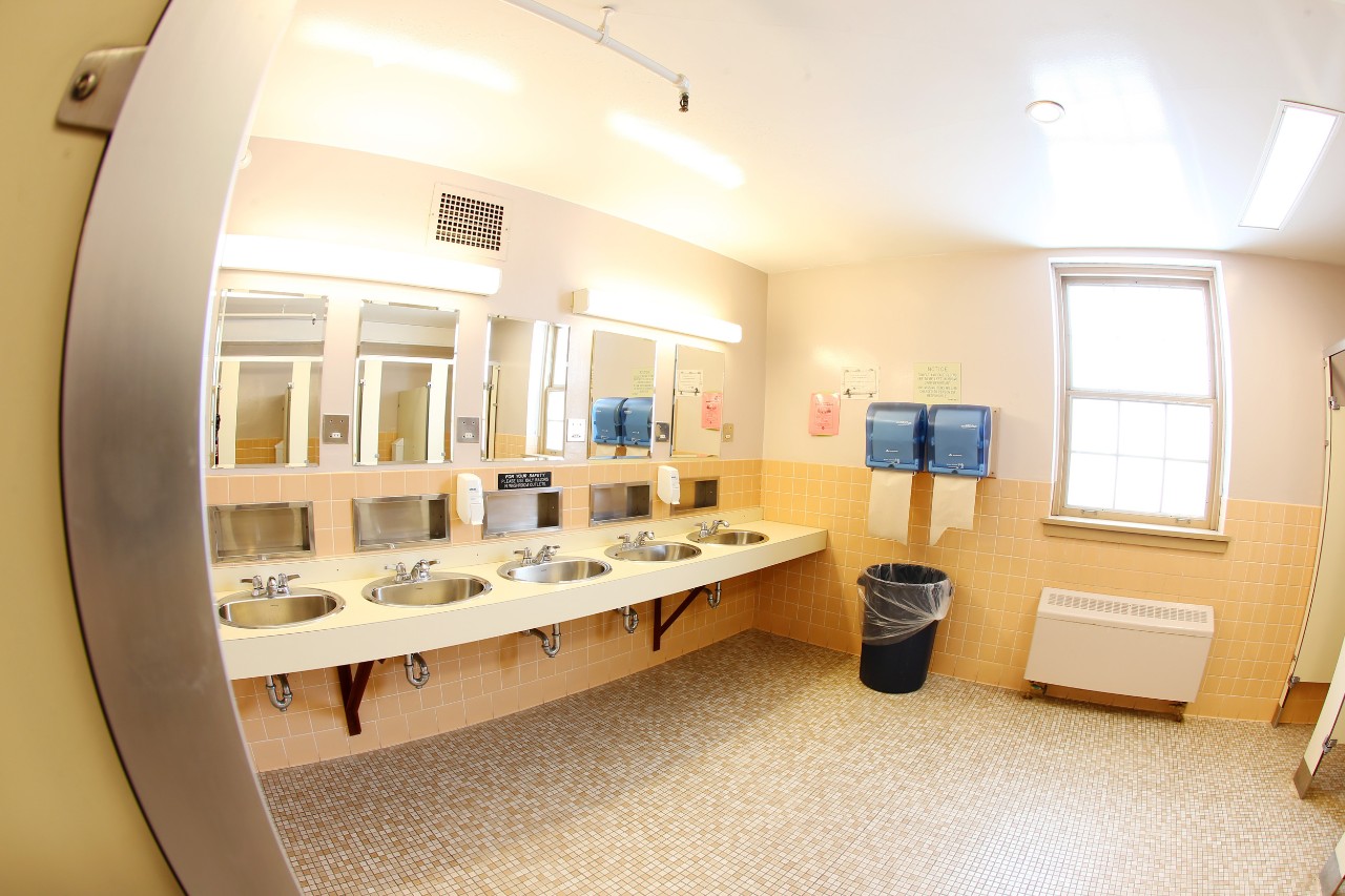 The sinks in a bathroom at Fraser House, with mirrors above each one and a tile floor.