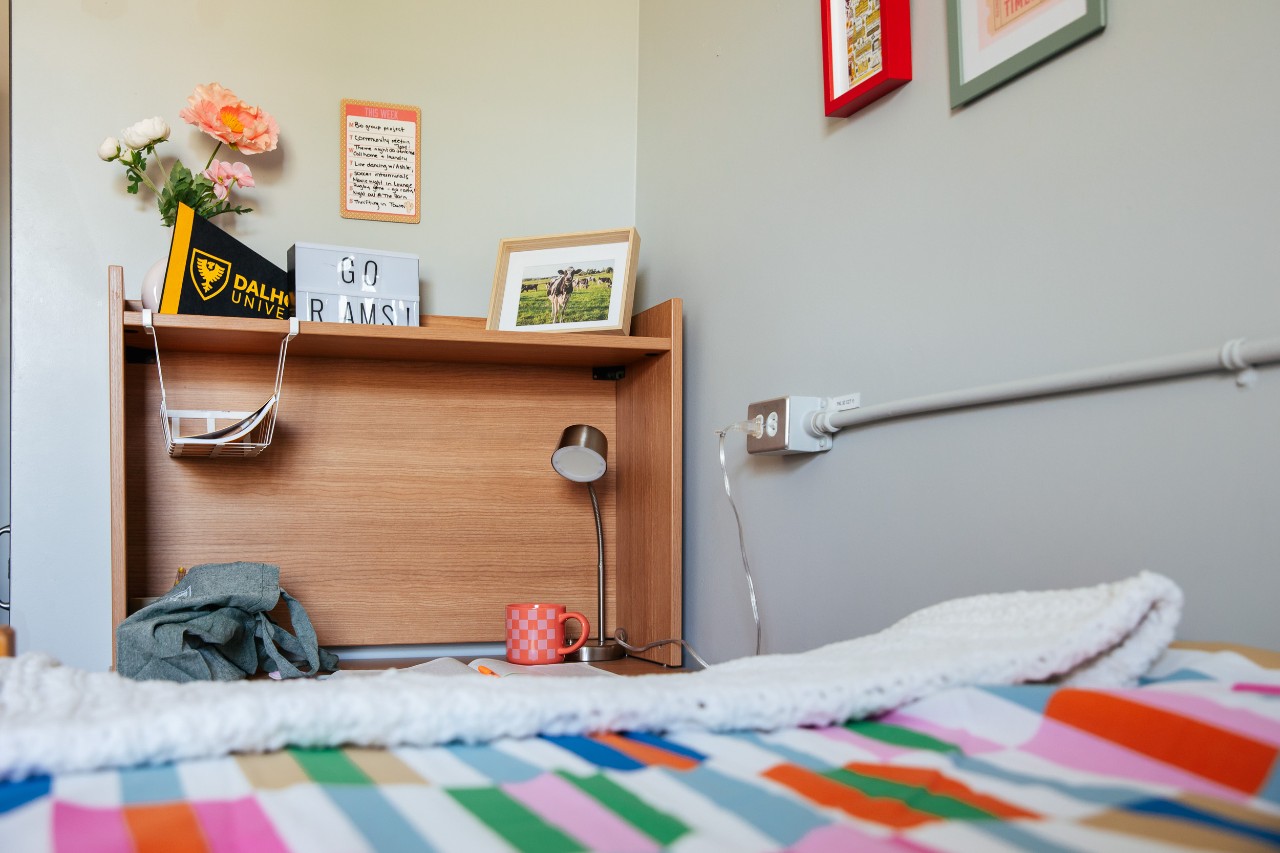 A closeup of a bed in a double room in Fraser House, showing the desk hutch with some personal decorations.