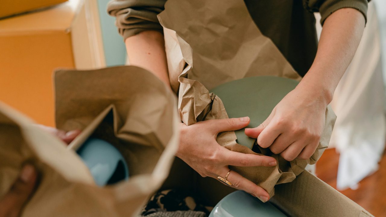 A person packs dishes in paper while preparing to move