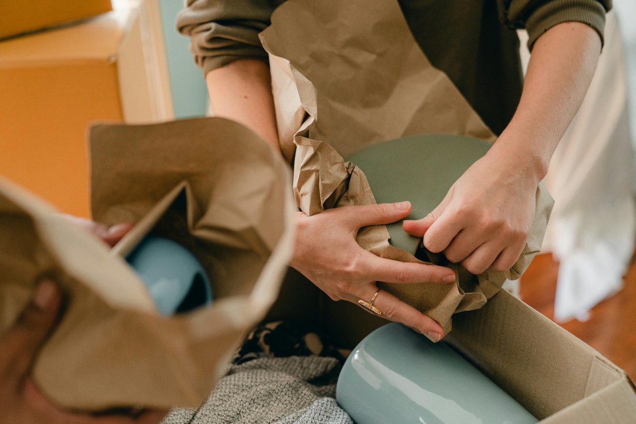 A person packs dishes in paper while preparing to move