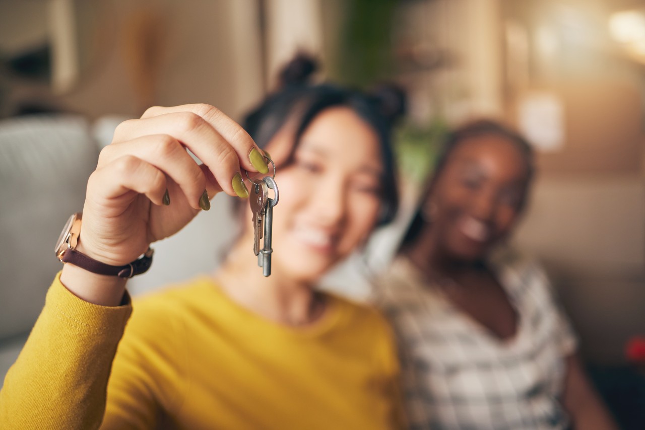 Two young women hold the keys to their new apartment