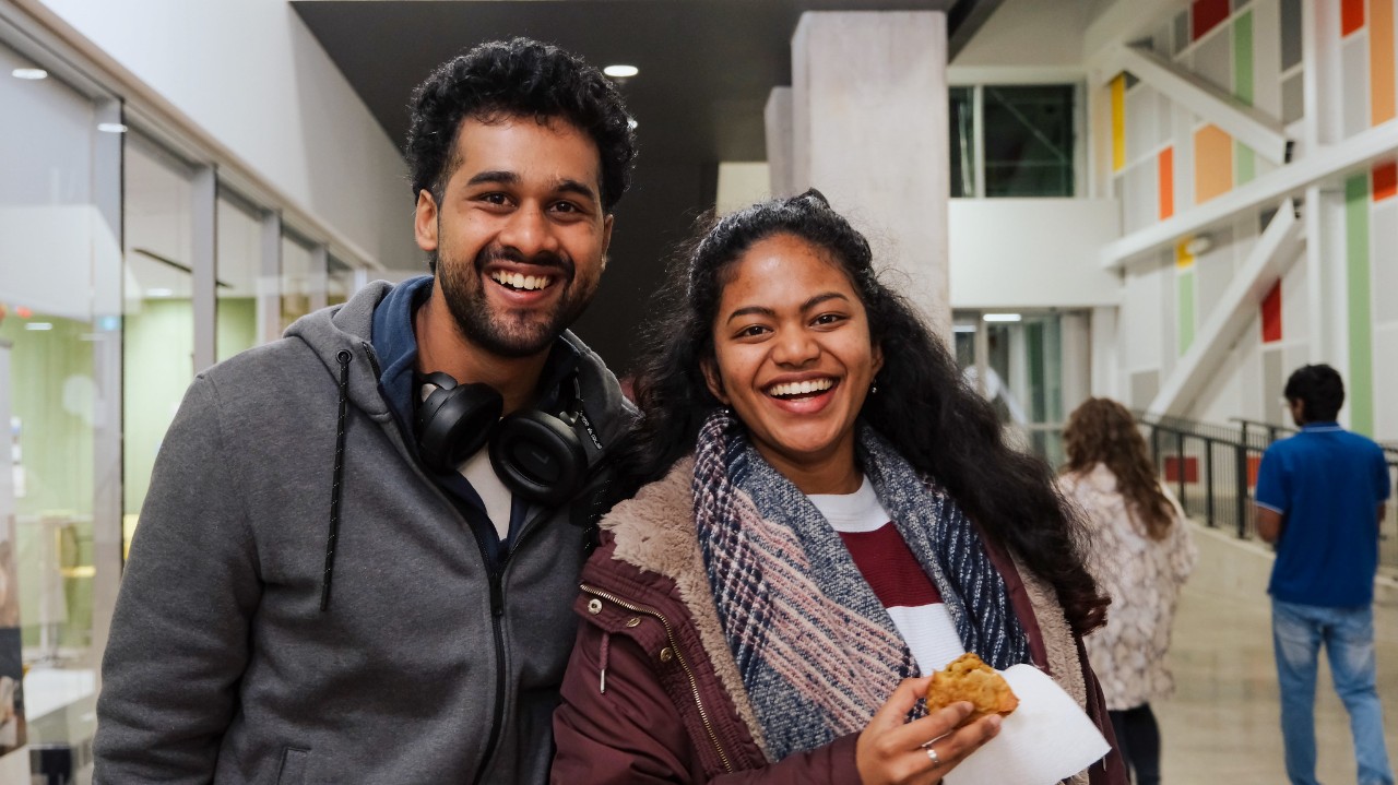 Two international students smiling at the camera at an event outside the International Centre.