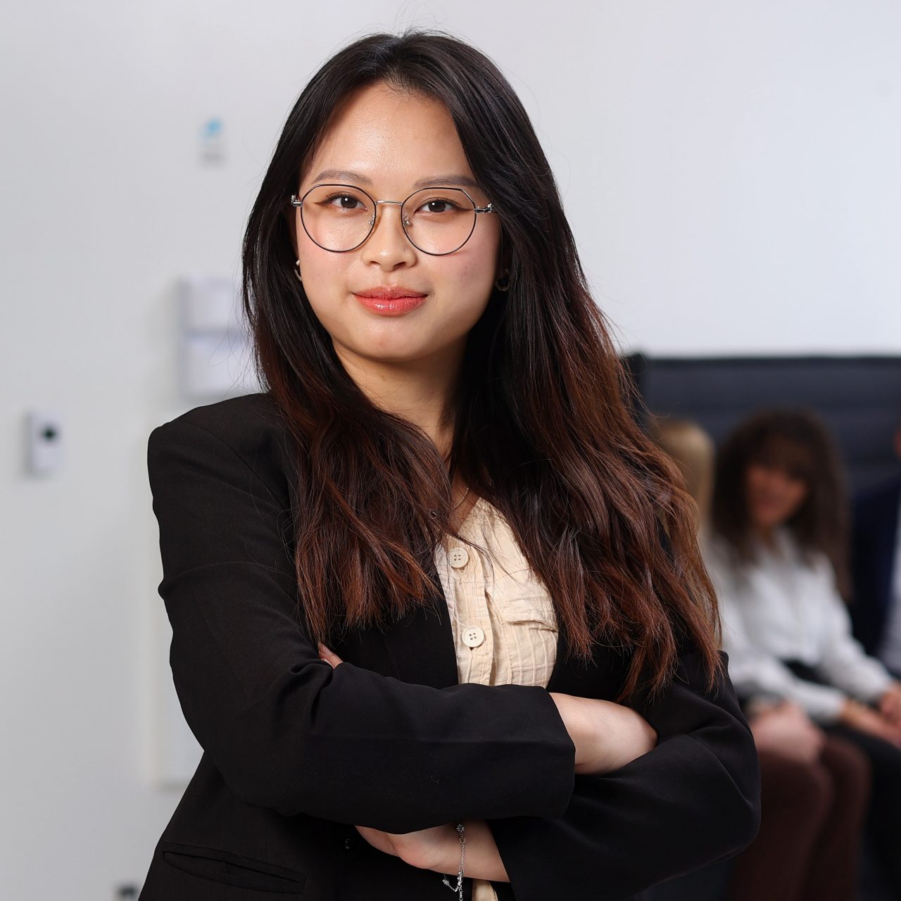 A student stands confidently, arms crossed, in an office building. 
