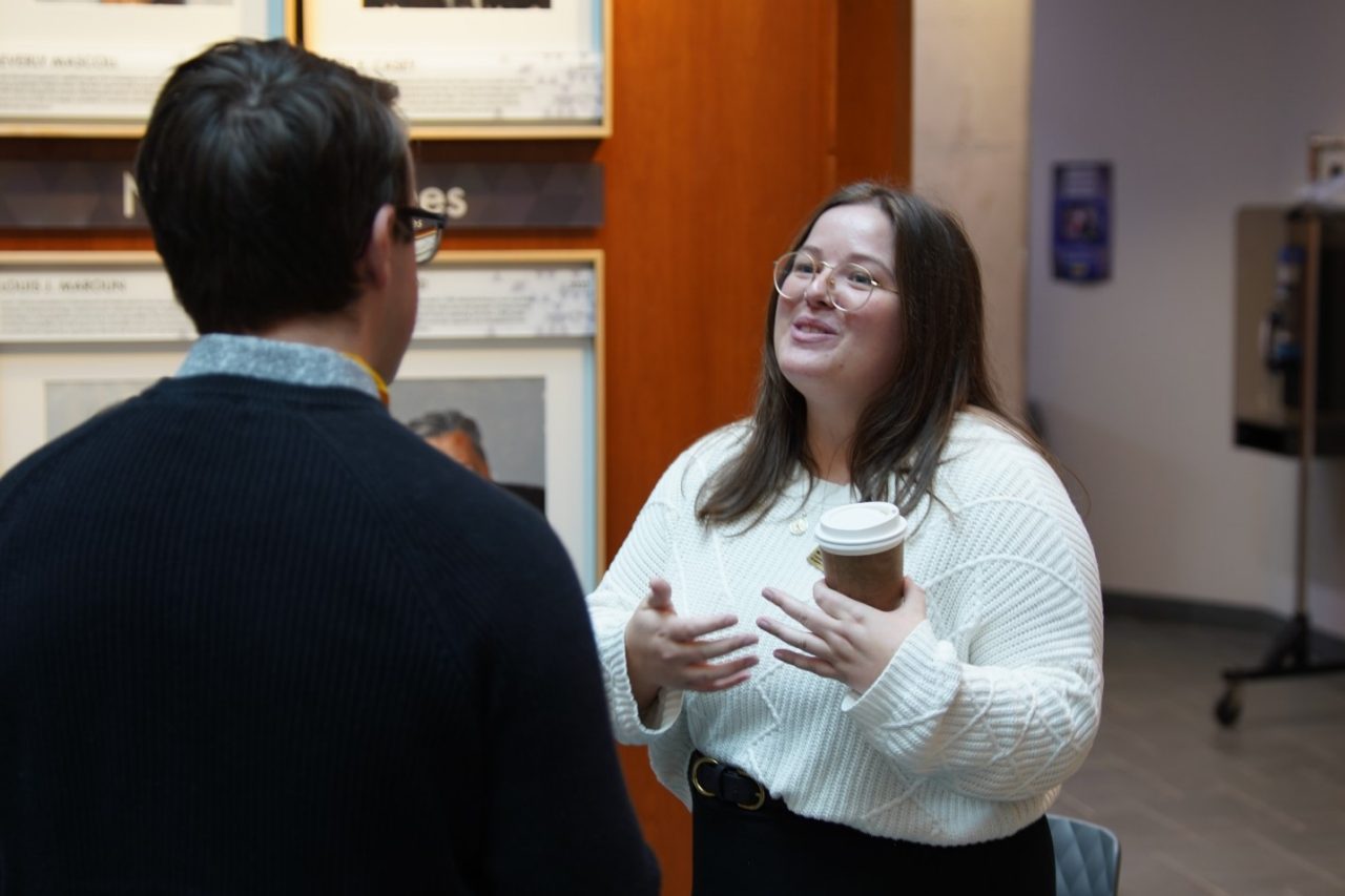 Michelle smiling, speaking to student, in lobby of the Rowe. 